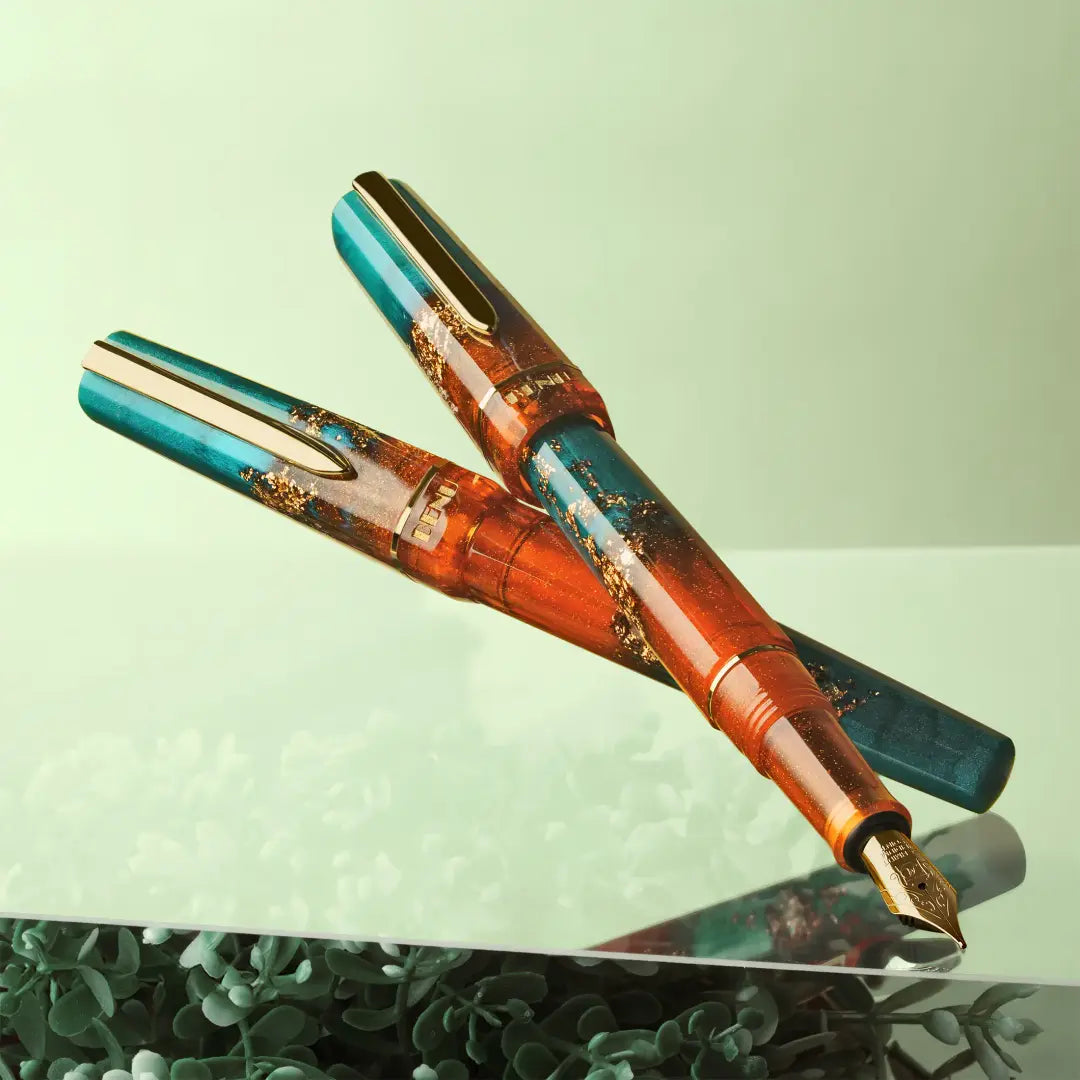 BENU presents the newest Haute Collection — a line of elegant, fashion-inspired pens that blend classic charm with bold, modern flair. The designs include both subtle and vibrant styles, showcasing BENU’s signature glitter and color artistry. Each pen features a faceted body with alternating wide and slender facets, complemented by either gold-plated or chrome-plated trims for a sleek, timeless look.
With a bold orange and teal body streaked with gold, Chic turns heads with runway-ready style. Fashion-forw