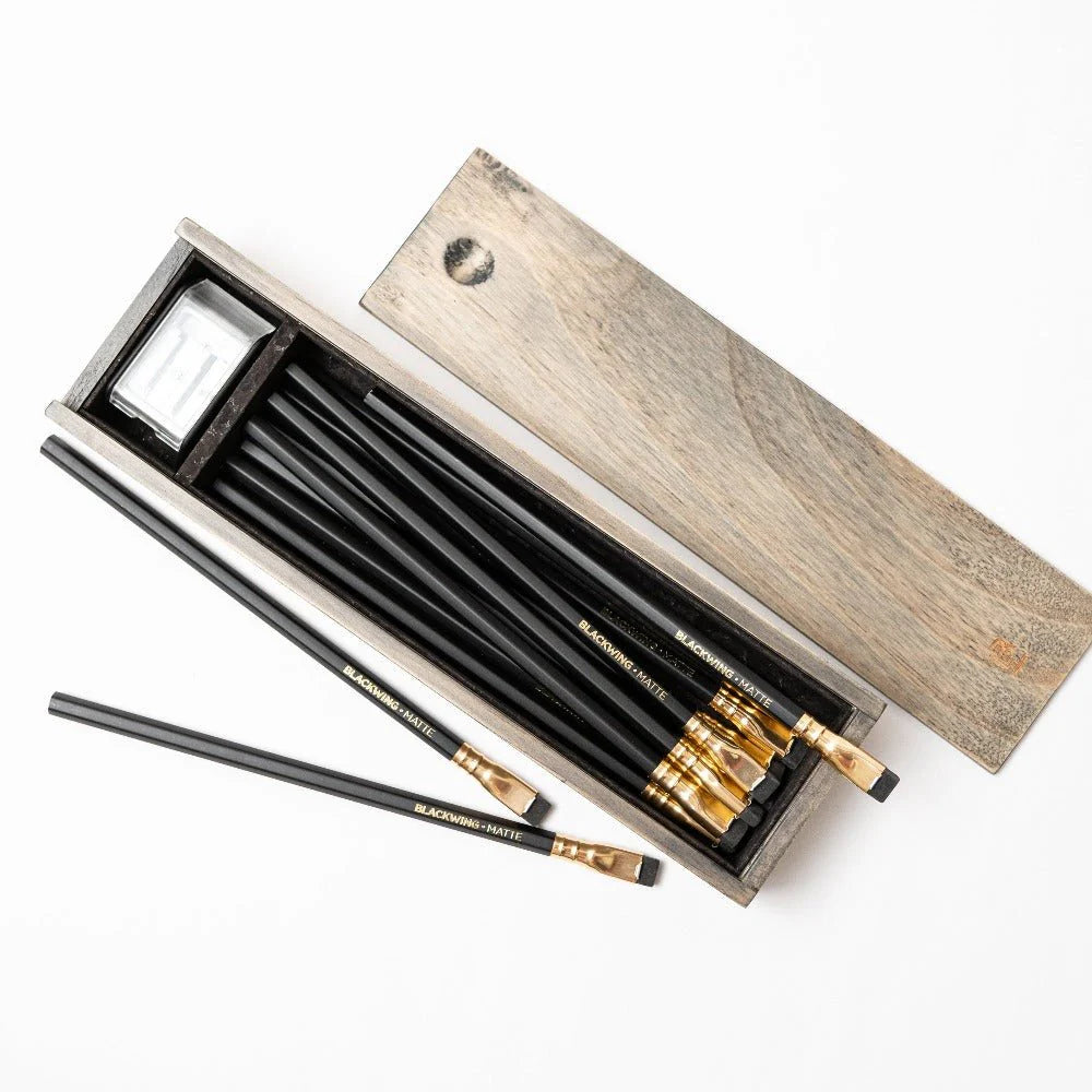 The Blackwing Rustic Box features your choice of 12 premium Blackwing graphite pencils and our reliable Two-Step Long Point Sharpener. Choose from 12 Matte pencils,12 602 pencils, 12 Pearl pencils, 12 Natural pencils, or 3 of each. The aged pine pencil box slides open to reveal the Blackwing pencils and a black cork-lined interior. The smooth stationery box is perfect for any workspace, office, or desk.