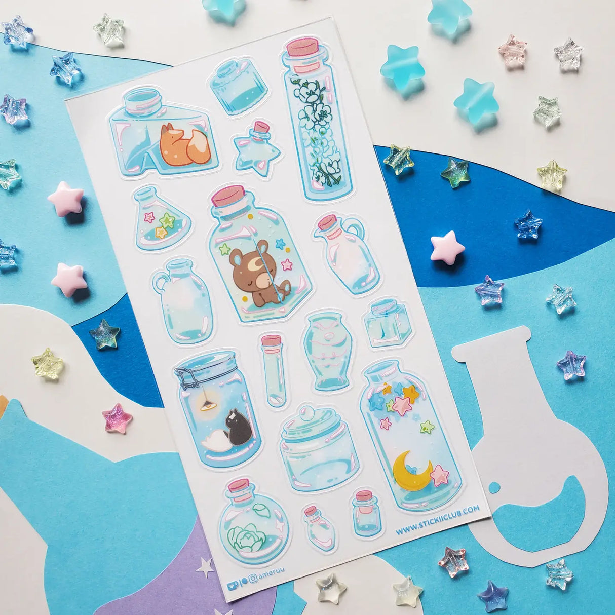 🌙🦊 Bottled up and brimming with magic, @ameruu transforms tiny jars into whole little worlds you can hold in your hands. Sleepy foxes and bears curl up for a nap, twinkling stars sparkle beside crescent moons, and delicate blooms and tiny treasures are tucked safely behind glass. From star-shaped vials to oversized bottles holding fragments of the night sky itself, this sheet is a pocket-sized universe, ready to sprinkle some stardust onto your favorite spreads.
Art by: @ameruu
