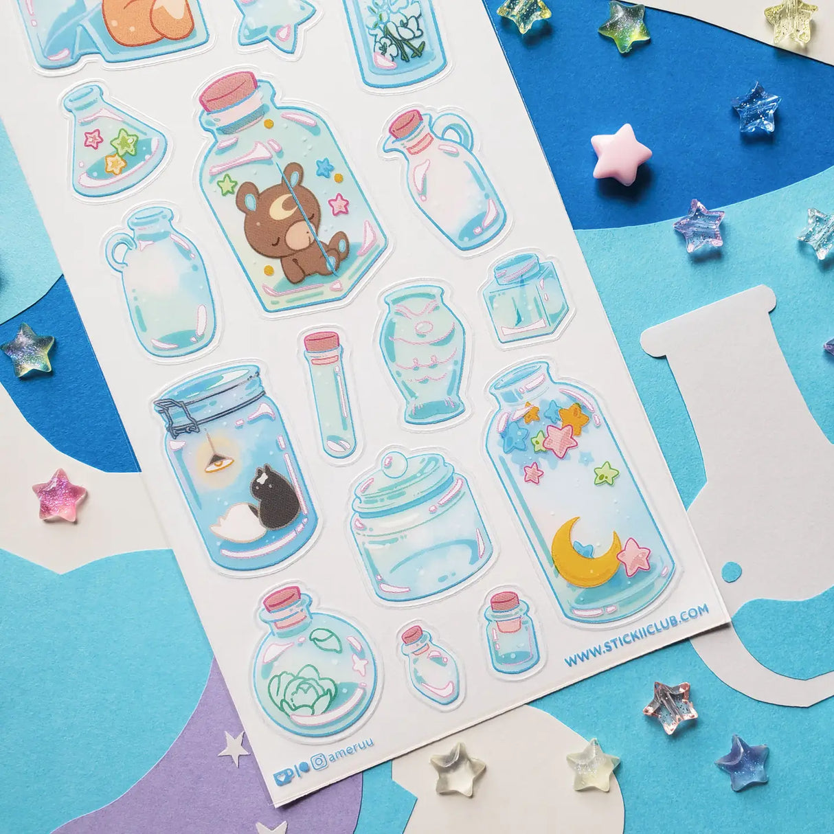🌙🦊 Bottled up and brimming with magic, @ameruu transforms tiny jars into whole little worlds you can hold in your hands. Sleepy foxes and bears curl up for a nap, twinkling stars sparkle beside crescent moons, and delicate blooms and tiny treasures are tucked safely behind glass. From star-shaped vials to oversized bottles holding fragments of the night sky itself, this sheet is a pocket-sized universe, ready to sprinkle some stardust onto your favorite spreads.
Art by: @ameruu