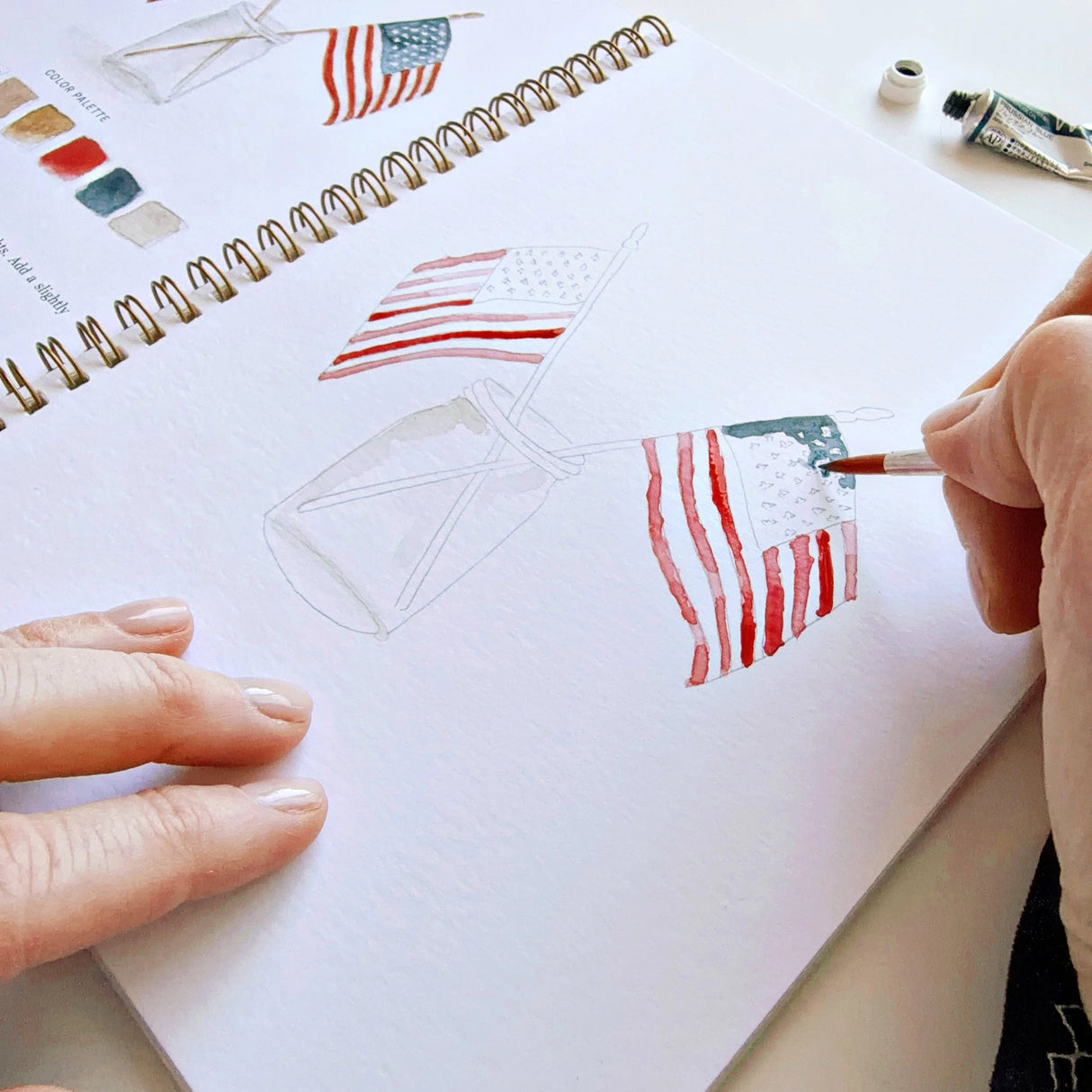 Twelve illustrations of flags, stars, and classic summer scenes — each pre-outlined with step-by-step instructions. Paintings take about thirty minutes from start to finish, making it approachable for first-time painters and a favorite for gifting.
A timely release for America's 250th anniversary in 2026. A strong May–July seller and a natural fit for home, gift, and patriotic-themed boutiques.
12 beginner-friendly illustrations
Thick 120lb watercolor paper
Lay-flat pages with spiral binding for has
