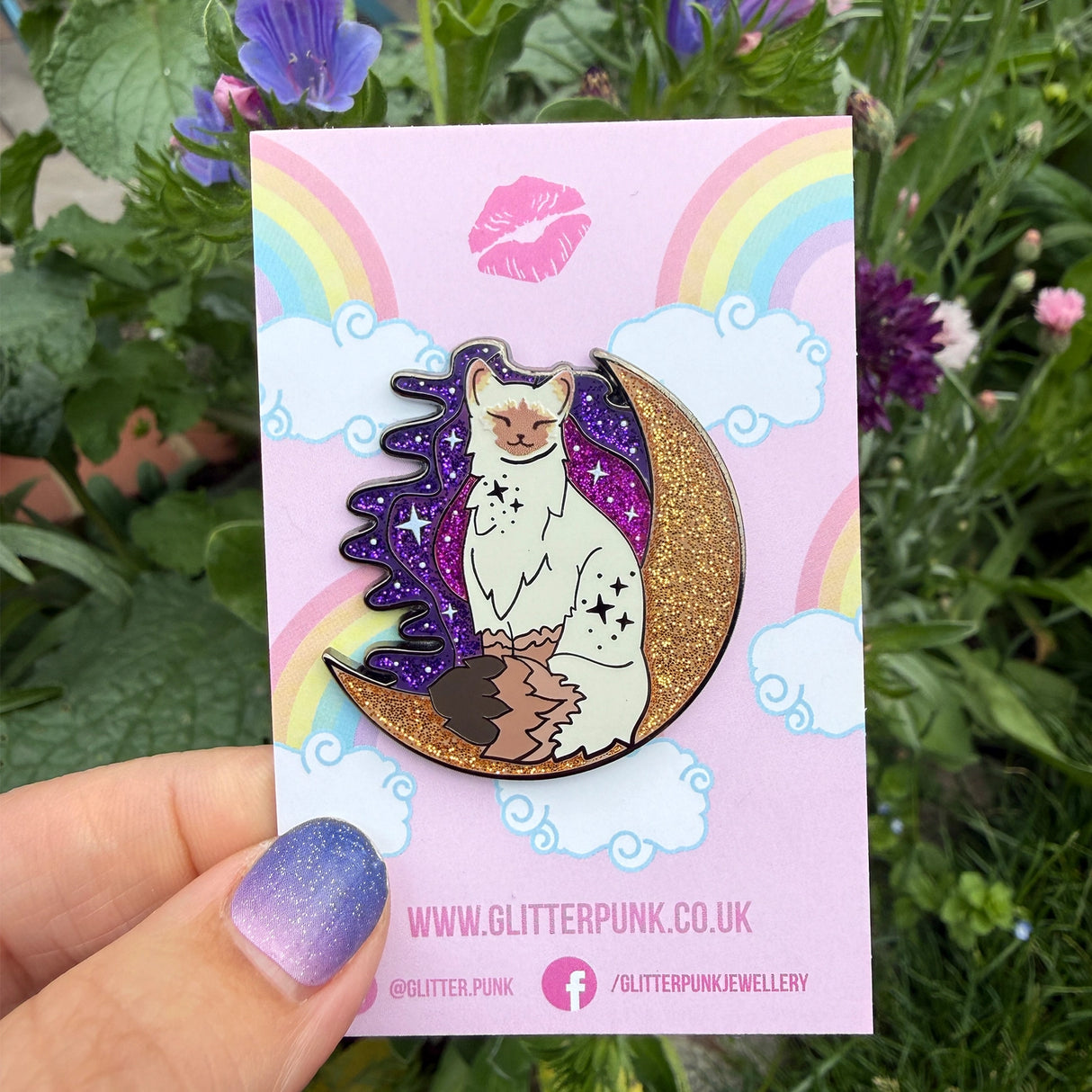 Calling all owners of a long haired pointed / meezer cats! This super cute design features the cat sitting in front of a sparkly moon with a glittery, starry sky in the background.
The pin is 40mm (1.57”) tall, and is made from gunmetal hard enamel, with glitter and UV printed details. It's secured with 2 pink clutches to keep the pin in place.