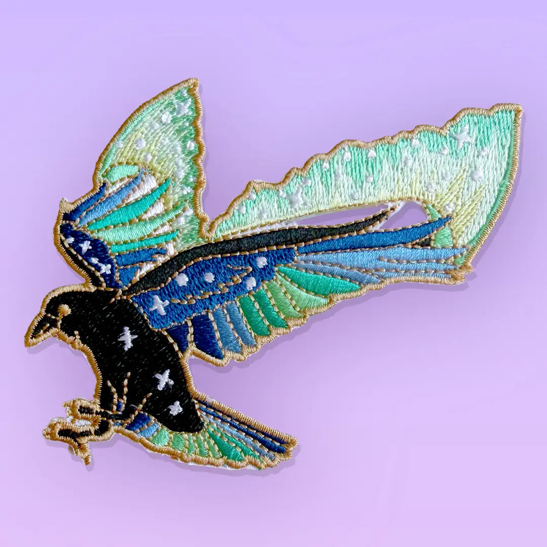 This amazing patch features a raven with its wings outstretched and the northern lights fanning out behind it.
Beautifully woven with black, green, blue & gold threads, this fabulous patch with brighten up any coat, bag or hat!
Measurements: 85 x 87mm