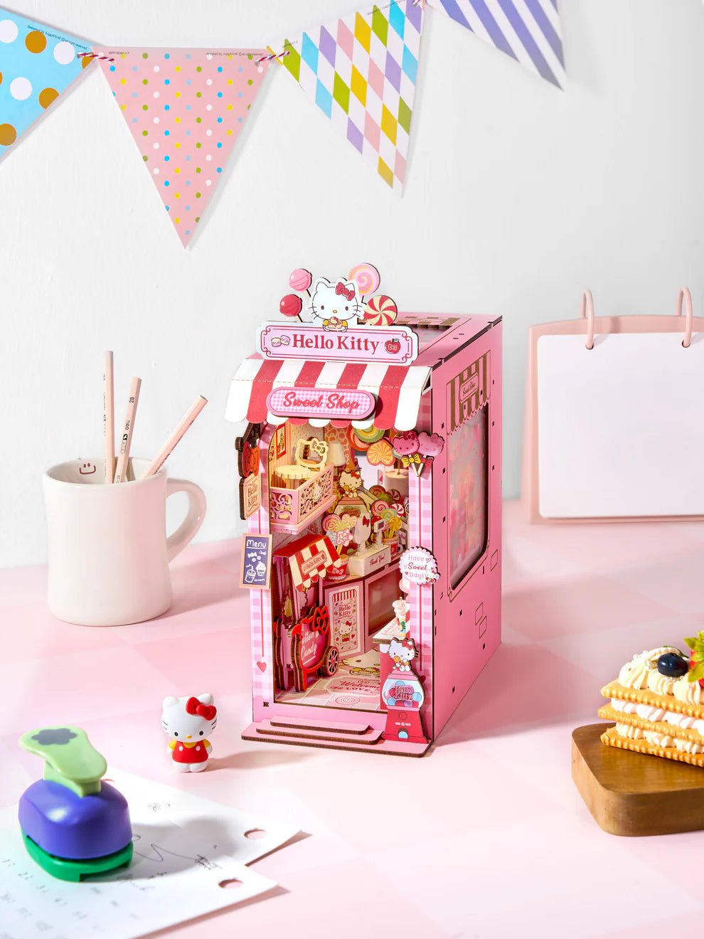 Step into a sugary dream with this irresistibly charming book nook kit, featuring Hello Kitty herself in a candy shop that's overflowing with sweetness and delight! From candy jars lining the shelves to pastel goodies peeking out from every corner, this magical miniature world is bursting with adorable, mouthwatering details.
And the showstopper? A dazzling lollipop chandelier that hangs like a crown jewel above the shop, casting a whimsical glow over the entire scene. It's a heart-melting centerpiece that