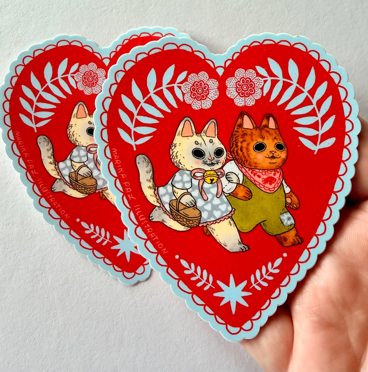 Two cats go for a walk on this folk art inspired sticker.
This vinyl matte sticker is weather and waterproof-stick it on a notebook, bike, or car- it's going to stick around! Heck, throw it on a water bottle and through the dishwasher. This sticker can go anywhere. Sticker measures 3.5" x 4.5" Printed in USA.