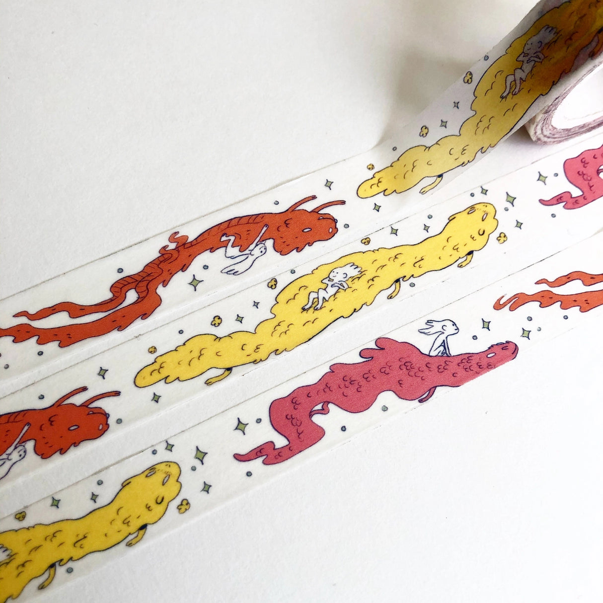 This Dragon washi tape features three soft, fluffy dragons that the dragon rider girl has befriended.
This roll is 15mm wide x 10m of paper tape. Washi tape is super durable and flexible. It tears easily and can be safely applied to a variety of surfaces; it doesn’t leave a sticky residue behind, making it especially ideal for stationery and hanging prints temporarily.