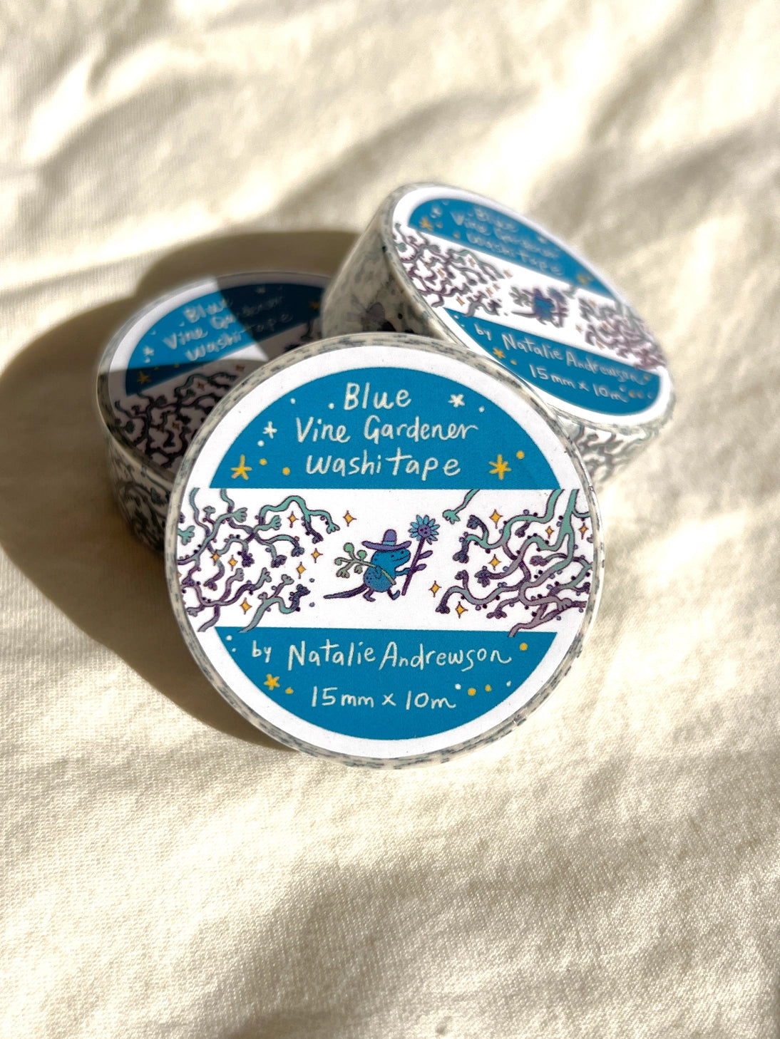 This washi tape features three little blue gardeners who work to keep the vines at bay.
This roll is 15mm wide x 10m of paper tape. Washi tape is super durable and flexible. It tears easily and can be safely applied to a variety of surfaces; it doesn’t leave a sticky residue behind, making it especially ideal for stationery and hanging prints temporarily.