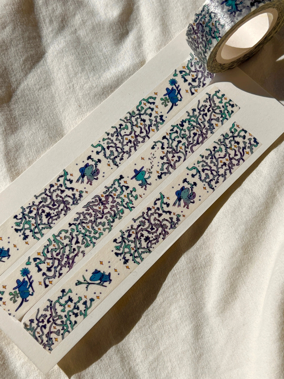 This washi tape features three little blue gardeners who work to keep the vines at bay.
This roll is 15mm wide x 10m of paper tape. Washi tape is super durable and flexible. It tears easily and can be safely applied to a variety of surfaces; it doesn’t leave a sticky residue behind, making it especially ideal for stationery and hanging prints temporarily.