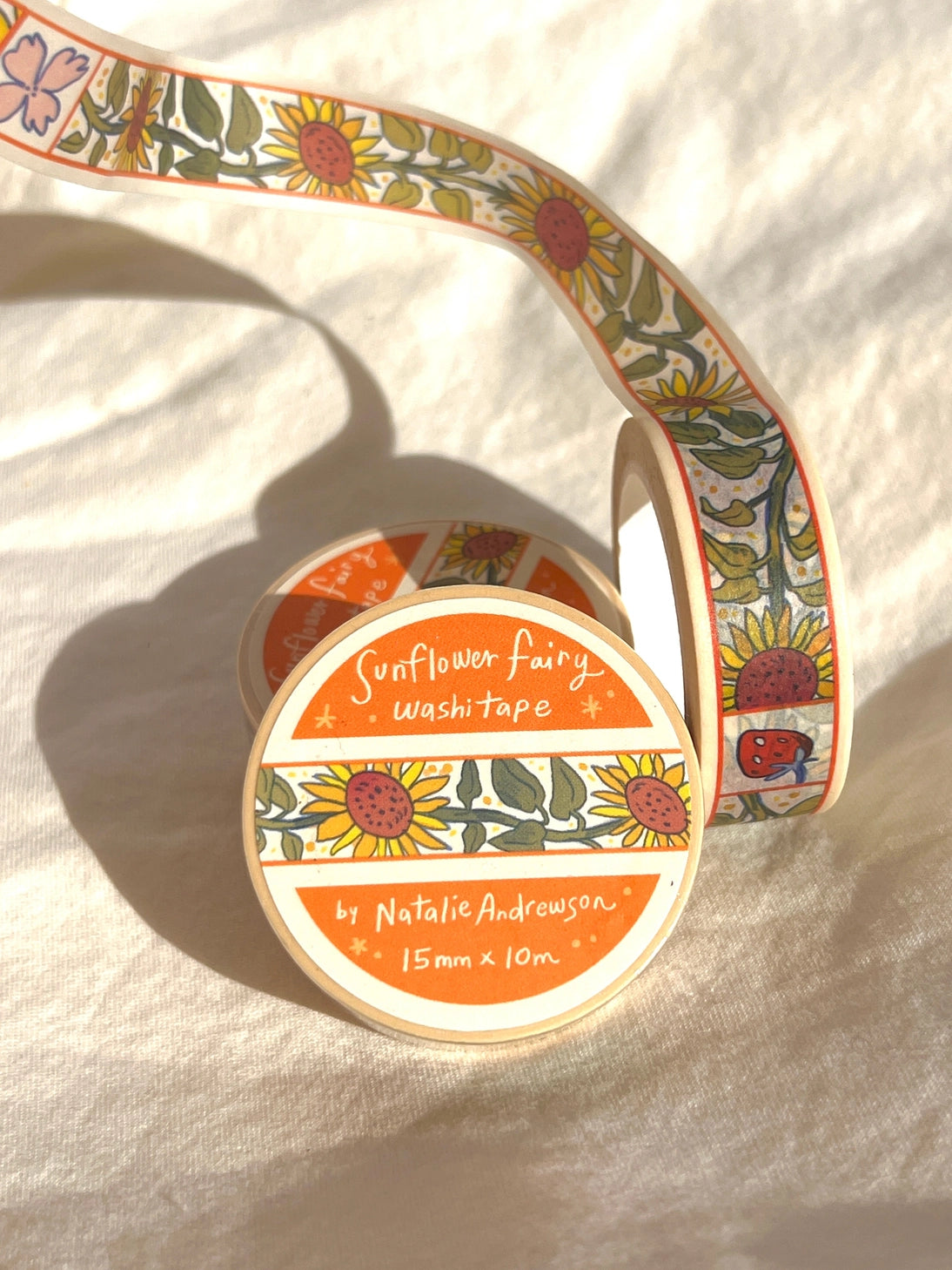 This washi tape features little sunflowers dancing one by one separated by flowers and strawberries. This tape design is taken from my Sunflower Fairy print's decorative borders.
This roll is 15mm wide x 10m of paper tape. Washi tape is super durable and flexible. It tears easily and can be safely applied to a variety of surfaces; it doesn’t leave a sticky residue behind, making it especially ideal for stationery and hanging prints temporarily.