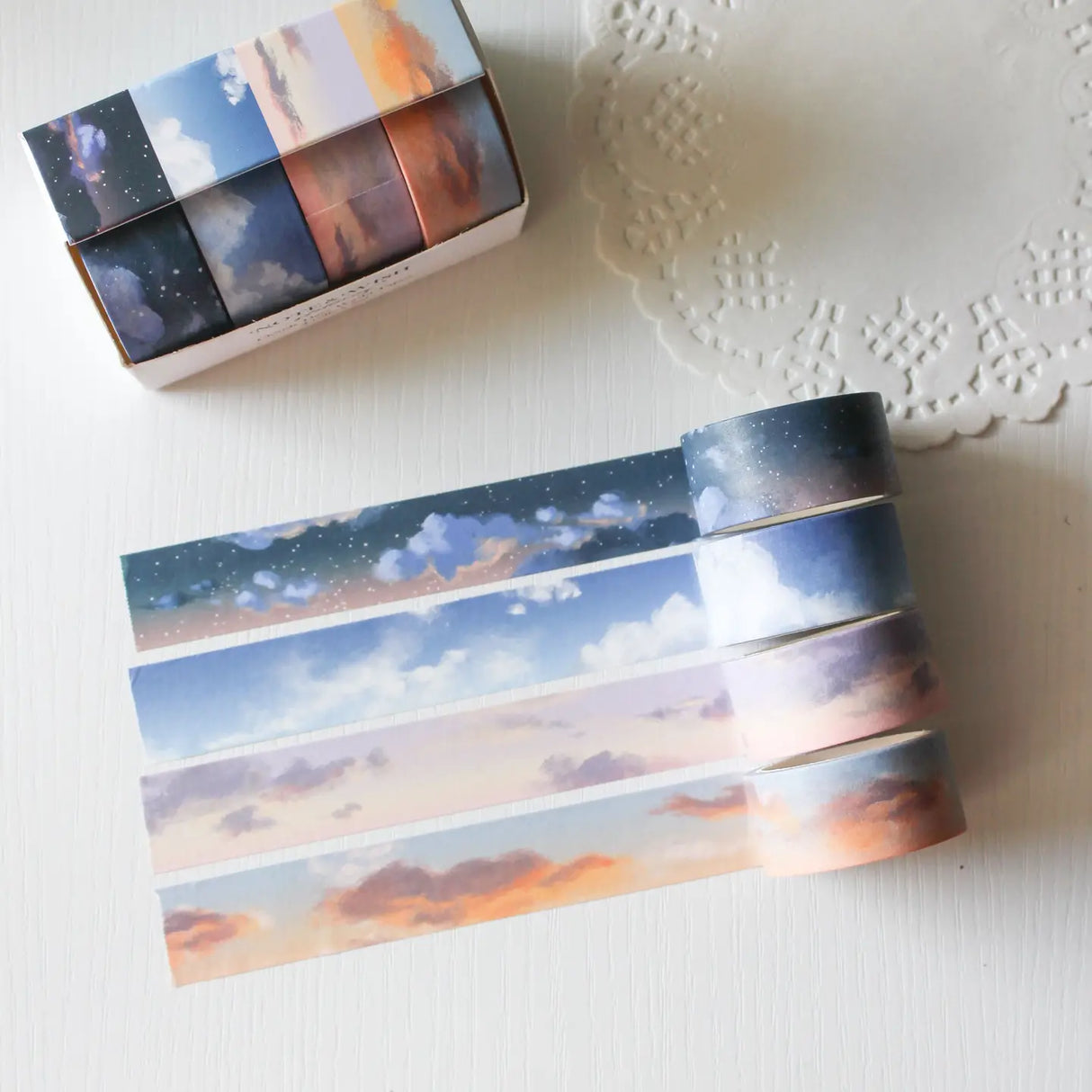 This washi tape box set is designed for journalers, sky gazers, and stationery lovers who find beauty in the ever-changing colours of the sky. Featuring four digitally drawn skyscape designs by Rebecca, each roll captures a different season, from soft spring sunrises to moody winter twilights, all packaged in a beautiful presentation box.
The four designs included:
* Cloudy Days Spring — soft purple and peach sunrise tones
* Cloudy Days Summer — sky blue with drifting white clouds 