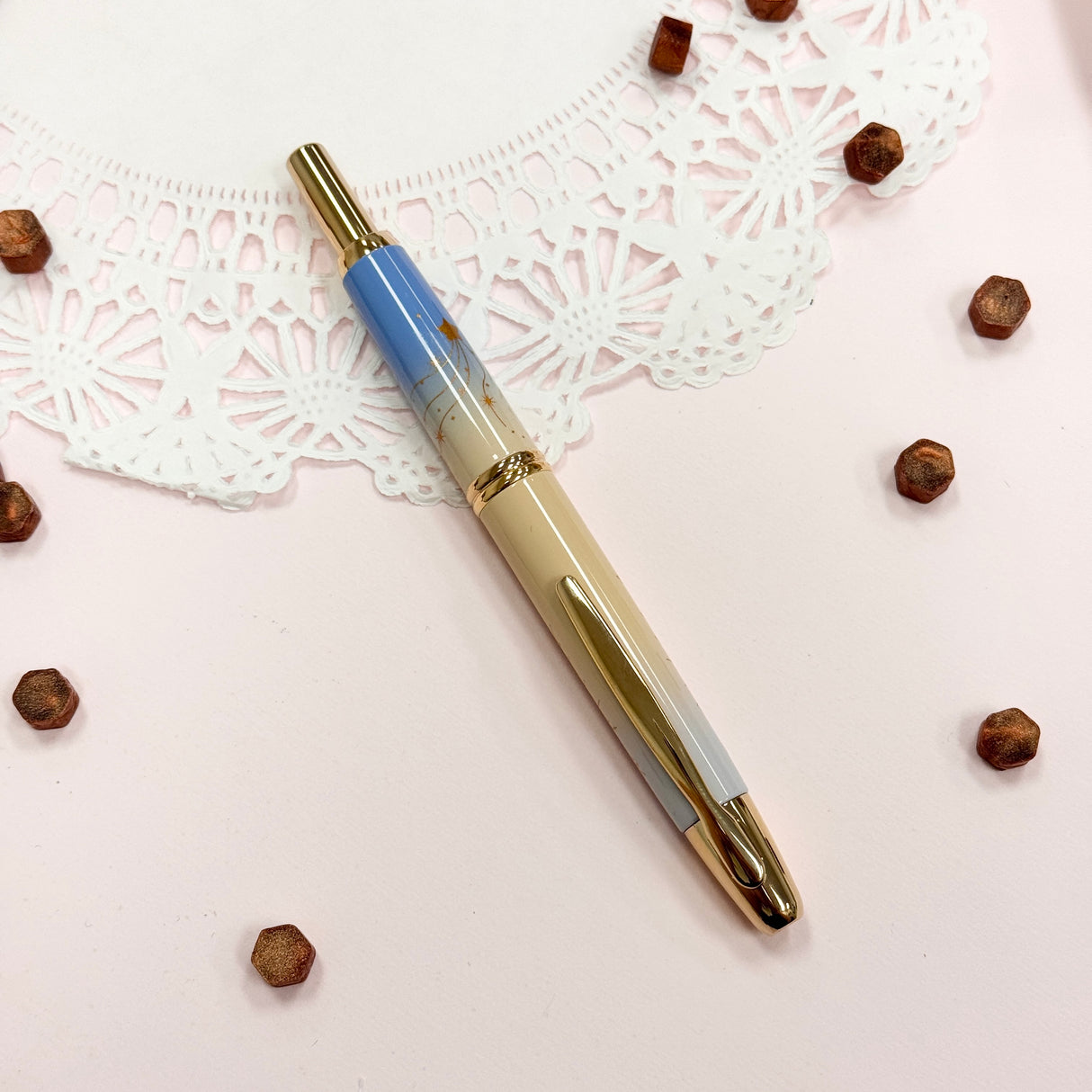 To commemorate 36 years of Kin Chi, this exclusive Pilot Capless “Starry Dawn” captures the quiet magic of the moment when night begins to surrender to morning.
Its softly layered colors move from pale blue through warm golden yellow and into a vivid morning blue, echoing the changing sky just before sunrise. Against the clouds, a radiant golden sun emerges while a scattering of stars still lingers above, an in-between moment where night and day meet.