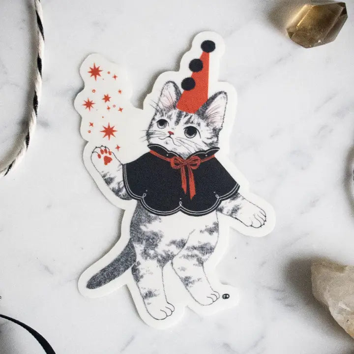 Unlock your inner magician with our Mystical Cat Magician Vinyl Sticker. This captivating sticker showcases a spellbinding feline conjuring sparkling stars and enchantment from the cosmic abyss. It's a symbol of the limitless enchantment that lies within you. Apply this sticker to any surface - it adheres effortlessly to your laptop, journal, water bottle, and more.