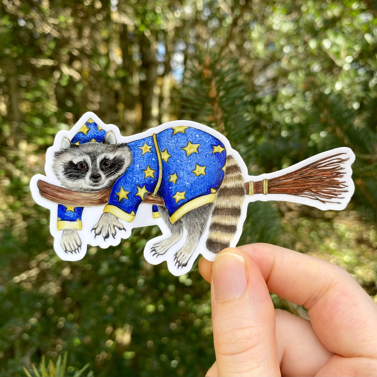 A sticker with my illustration of a wizard raccoon riding on a broom.
This die-cut vinyl sticker is durable and perfect for water bottles, notebooks, laptops, bikes, and all sorts of other surfaces! Make sure to clean and dry the surface thoroughly before applying.