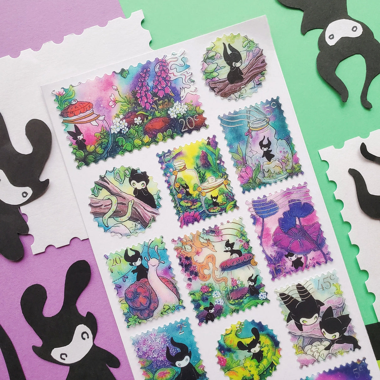 🌳🍄 Stamp your passport and hang on to it tight or one of these cuties might get curious! This whimsical sheet by @pabkins features curious little forest spirits that dart between mushrooms, bottle secret spells, ride friendly snails, and splash through ancient streams. They got a penchant for exploring, and they want you to join (sometimes unknowingly!)
Art by: @pabkins
Top Coating: Silver foil
Adhesive Layer: Paper
Backing Layer: Clear PET
6.69" x 3.54".
Weight - 0.03lbs.
1 sheet incl