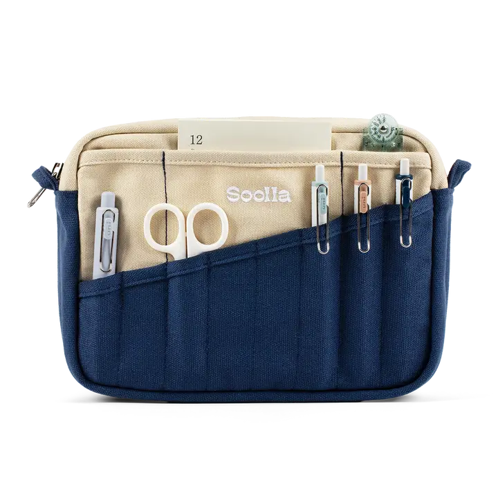 A compact carry-all pouch for artists, makers, and stationary lovers who appreciate a little order in their chaos. Structured enough to hold its form, soft enough to fit anywhere, and fully machine-washable for the days that get a little messy — your tools, pens, and creative essentials stay safe, visible, and ready wherever you go.
Inside, 20 pockets make space for art supplies, stationary essentials, and an A5 notebook, all secured by a smooth YKK zipper. Sized to fit within larger bags or carry on its o