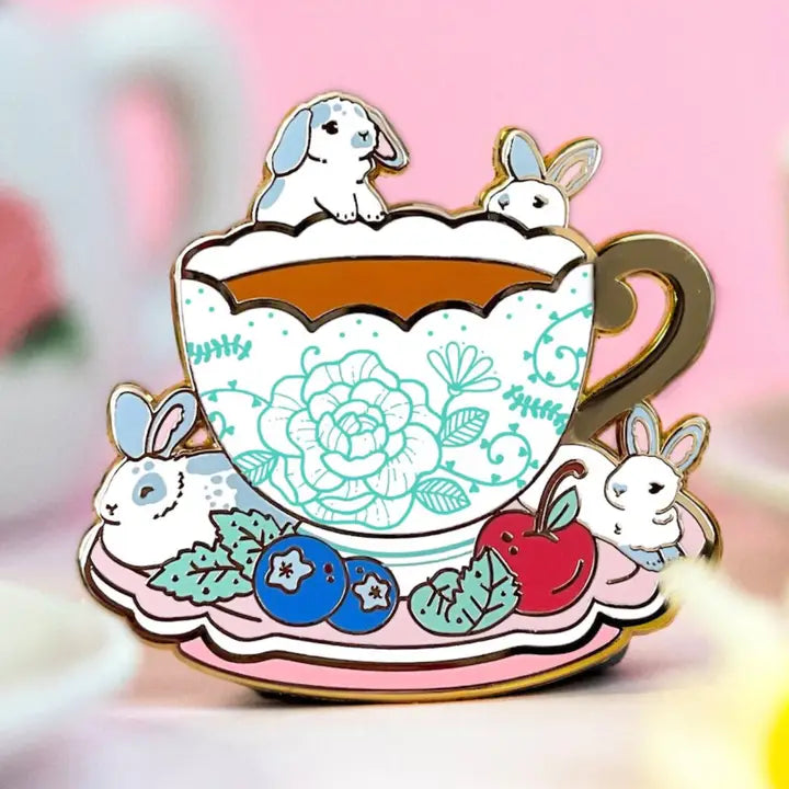 These pastel bunnies are spending a relaxing day amongst blueberries, cherries, and yummy tea inside an intricately decorated cup.
✦ Hard enamel
✦ Shiny gold metal
✦ 1.75 inches
✦ 2 Posts for extra security
✦ Rubber backings
✦ Back stamped for authenticity
Comes packaged on a backing card.