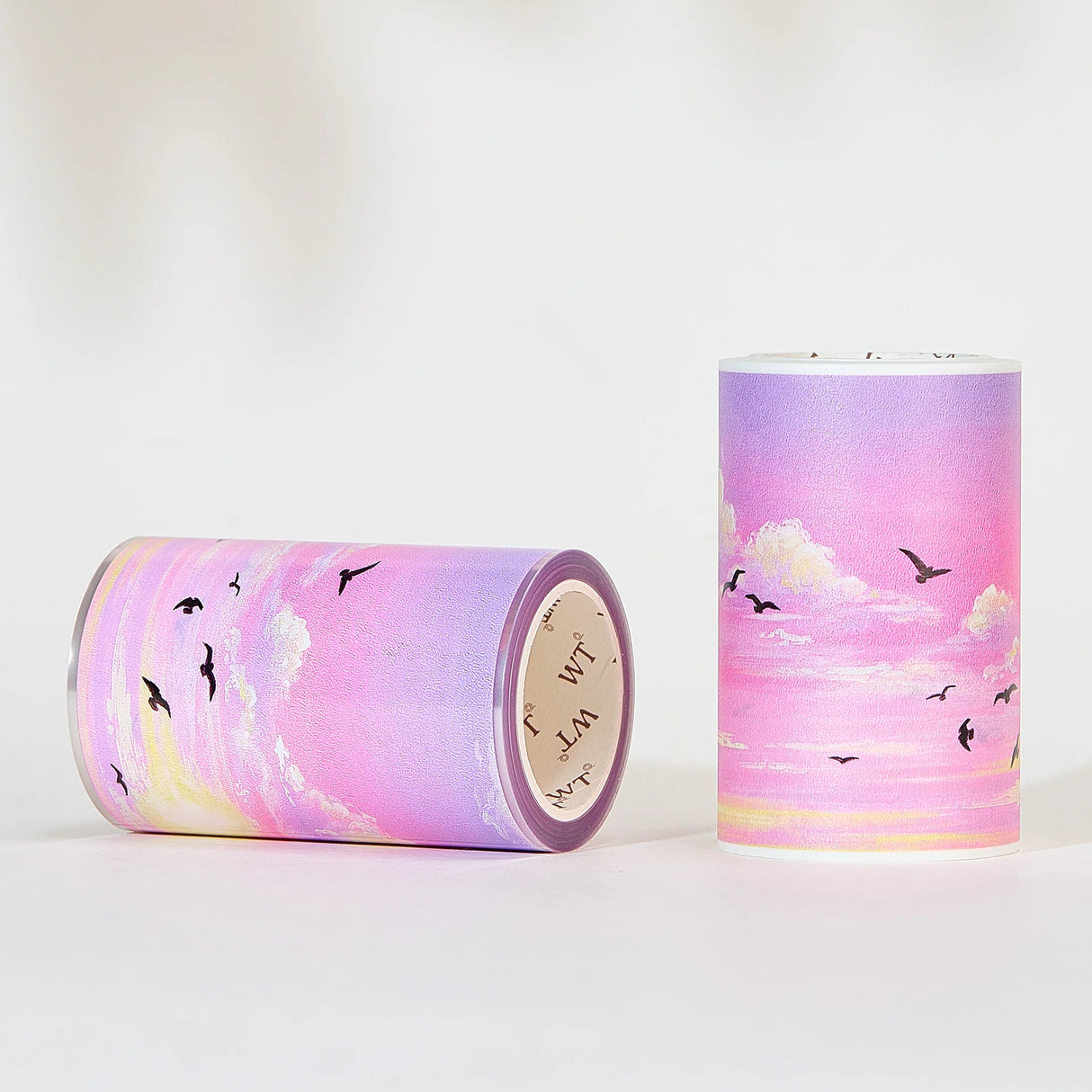 Capture the gentle embrace of evening with the Lotus Twilight Wide Washi/PET Tape. This tape embodies the softest part of the sunset. The design features a dreamy, seamless gradient that flows from a warm, glowing orange into a hazy, light lavender. Drifting through this pastel sky is a flock of silhouetted birds, gliding peacefully on the breeze. It brings a sense of calm and whimsy to your journal, perfectly replicating that quiet, cotton-candy sky moment just before the stars come out.