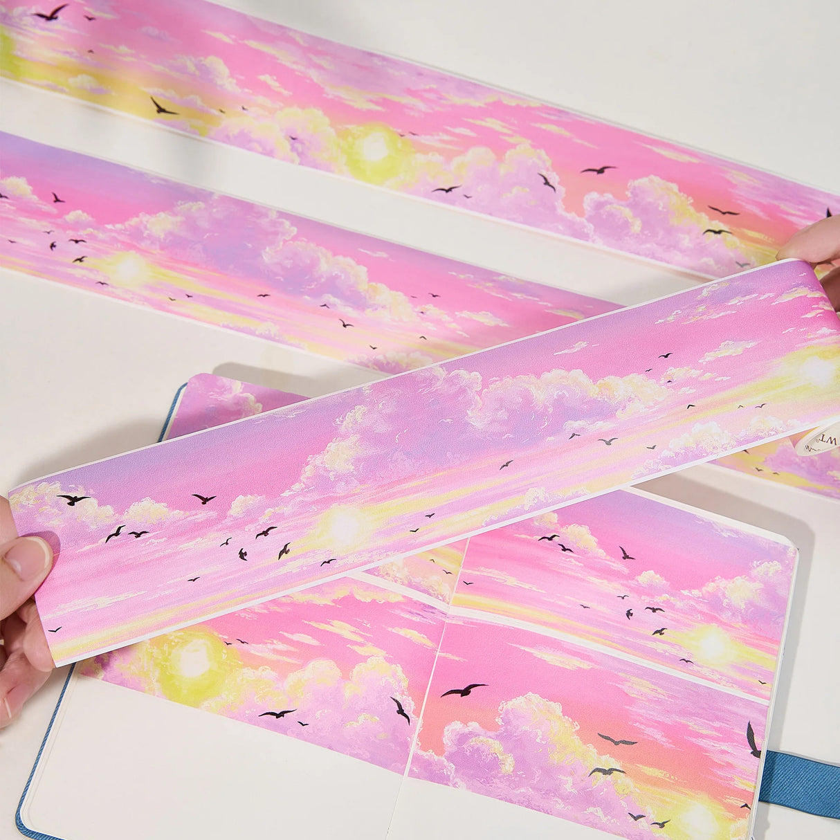 Capture the gentle embrace of evening with the Lotus Twilight Wide Washi/PET Tape. This tape embodies the softest part of the sunset. The design features a dreamy, seamless gradient that flows from a warm, glowing orange into a hazy, light lavender. Drifting through this pastel sky is a flock of silhouetted birds, gliding peacefully on the breeze. It brings a sense of calm and whimsy to your journal, perfectly replicating that quiet, cotton-candy sky moment just before the stars come out.