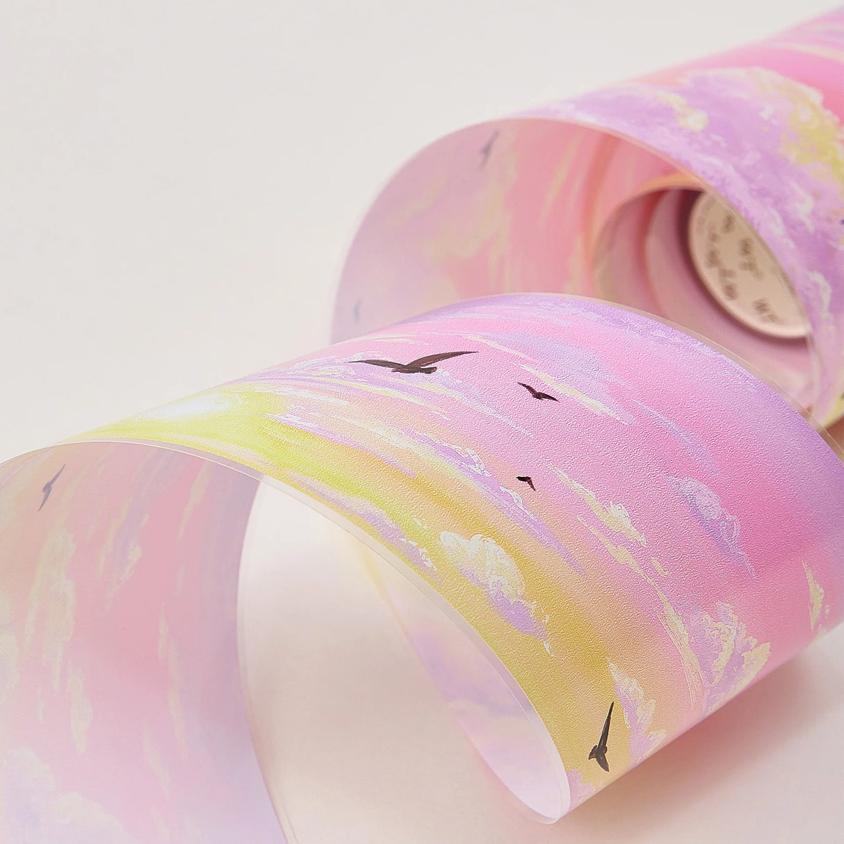 Capture the gentle embrace of evening with the Lotus Twilight Wide Washi/PET Tape. This tape embodies the softest part of the sunset. The design features a dreamy, seamless gradient that flows from a warm, glowing orange into a hazy, light lavender. Drifting through this pastel sky is a flock of silhouetted birds, gliding peacefully on the breeze. It brings a sense of calm and whimsy to your journal, perfectly replicating that quiet, cotton-candy sky moment just before the stars come out.