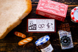 Small jars, a loaf of bread, and decorative boxes on a wooden surface