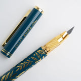 A beautifully designed craft knife featuring a deep teal barrel adorned with gold botanical detailing. With its precision blade and sturdy metal construction, this tool brings both function and elegance to journaling, scrapbooking, and detailed paper crafting.

Specs &amp; Details:

Material: Metal body with gold accents
Design Theme: Teal barrel with gold botanical illustration
Blade: Precision craft blade (replaceable)
Features: Removable cap for safe storage, textured grip for control
Use: Ideal for cutt
