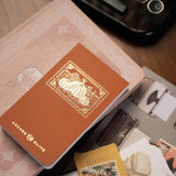 Capture fleeting thoughts, favorite quotes, and creative ideas with the Quiet Corners Memo Pad. 

Wrapped in a beautiful buckram cover with elegant gold foil details, this compact memo pad is designed to stay close at hand whenever inspiration strikes. 

Whether tucked into your bag or resting beside your journal, it's the perfect companion for writers, readers, and everyday note-takers.