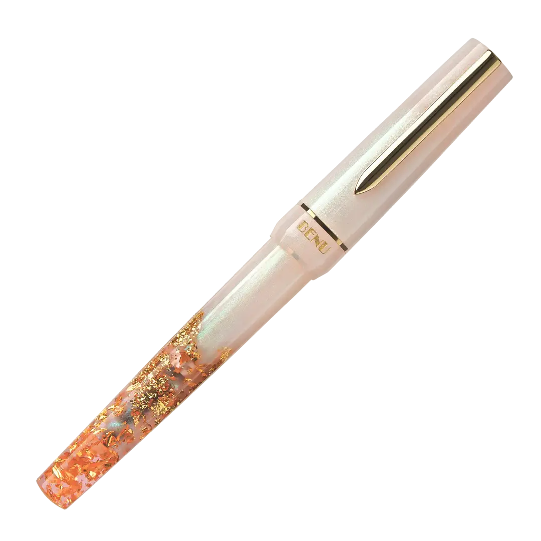 BENU presents the newest Haute Collection — a line of elegant, fashion-inspired pens that blend classic charm with bold, modern flair. The designs include both subtle and vibrant styles, showcasing BENU’s signature glitter and color artistry. Each pen features a faceted body with alternating wide and slender facets, complemented by either gold-plated or chrome-plated trims for a sleek, timeless look.

A mix of golden flakes dances through a soft, pearly pink base, complemented by gleaming gold trim. Tender 
