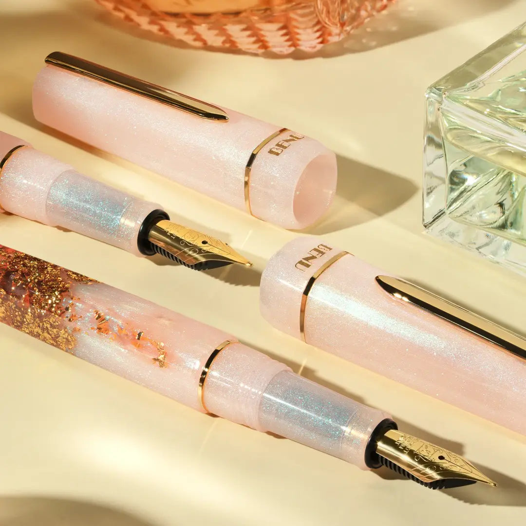 BENU presents the newest Haute Collection — a line of elegant, fashion-inspired pens that blend classic charm with bold, modern flair. The designs include both subtle and vibrant styles, showcasing BENU’s signature glitter and color artistry. Each pen features a faceted body with alternating wide and slender facets, complemented by either gold-plated or chrome-plated trims for a sleek, timeless look.

A mix of golden flakes dances through a soft, pearly pink base, complemented by gleaming gold trim. Tender 