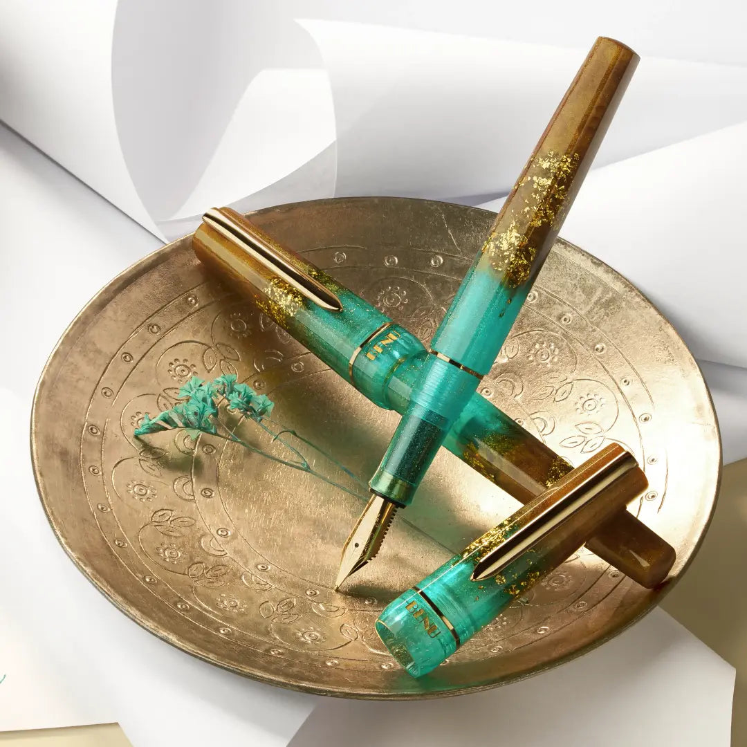 BENU presents the newest Haute Collection — a line of elegant, fashion-inspired pens that blend classic charm with bold, modern flair. The designs include both subtle and vibrant styles, showcasing BENU’s signature glitter and color artistry. Each pen features a faceted body with alternating wide and slender facets, complemented by either gold-plated or chrome-plated trims for a sleek, timeless look.

Seal and caramel tones swirl together, flecked with radiant gold. Lush evokes runway opulence — bold, textu