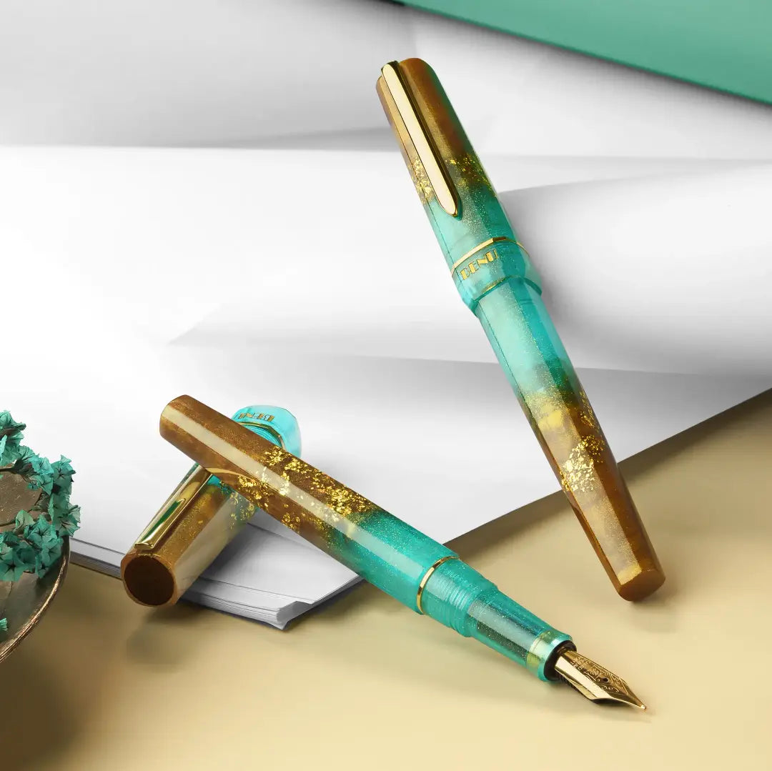 BENU presents the newest Haute Collection — a line of elegant, fashion-inspired pens that blend classic charm with bold, modern flair. The designs include both subtle and vibrant styles, showcasing BENU’s signature glitter and color artistry. Each pen features a faceted body with alternating wide and slender facets, complemented by either gold-plated or chrome-plated trims for a sleek, timeless look.

Seal and caramel tones swirl together, flecked with radiant gold. Lush evokes runway opulence — bold, textu