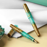 BENU presents the newest Haute Collection — a line of elegant, fashion-inspired pens that blend classic charm with bold, modern flair. The designs include both subtle and vibrant styles, showcasing BENU’s signature glitter and color artistry. Each pen features a faceted body with alternating wide and slender facets, complemented by either gold-plated or chrome-plated trims for a sleek, timeless look.

Seal and caramel tones swirl together, flecked with radiant gold. Lush evokes runway opulence — bold, textu