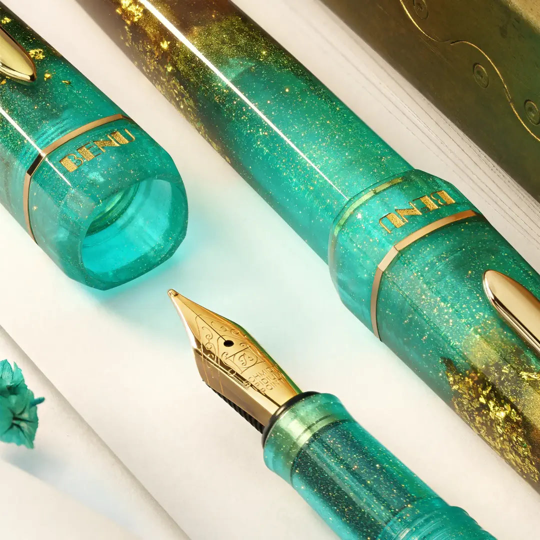 BENU presents the newest Haute Collection — a line of elegant, fashion-inspired pens that blend classic charm with bold, modern flair. The designs include both subtle and vibrant styles, showcasing BENU’s signature glitter and color artistry. Each pen features a faceted body with alternating wide and slender facets, complemented by either gold-plated or chrome-plated trims for a sleek, timeless look.

Seal and caramel tones swirl together, flecked with radiant gold. Lush evokes runway opulence — bold, textu