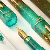 BENU presents the newest Haute Collection — a line of elegant, fashion-inspired pens that blend classic charm with bold, modern flair. The designs include both subtle and vibrant styles, showcasing BENU’s signature glitter and color artistry. Each pen features a faceted body with alternating wide and slender facets, complemented by either gold-plated or chrome-plated trims for a sleek, timeless look.

Seal and caramel tones swirl together, flecked with radiant gold. Lush evokes runway opulence — bold, textu