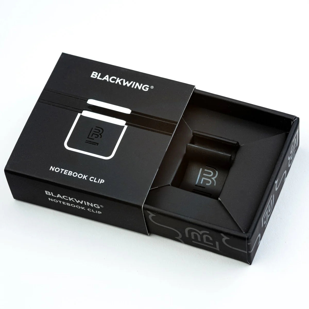 The Blackwing Notebook Clip is designed to keep your pencil and paper together. The clip is made of aluminum and finished with our signature matte black texture. Once you attach the reusable clip to your notebook, your pencil snaps into a durable thermoplastic polymer that won't scuff the lacquer. Perfect for everyday carry—clip it onto your spiral notebook, legal pad, memo book, or reading book to keep your stationery organized.
