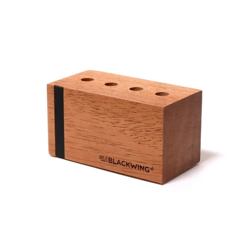 This solid wood pencil display is made with mahogany and is designed to showcase four upright Blackwing pencils. Display the four core Blackwing pencils, or choose four of your favorite designs to add some character to your desk. This display fits well on a desk or shelf, or you can hang it using the predrilled mounting holes. Blackwing logo engraved on the side.

The Blackwing Upright Four Pencil display measures 3.5 x 1.75 x 1.875 inches.