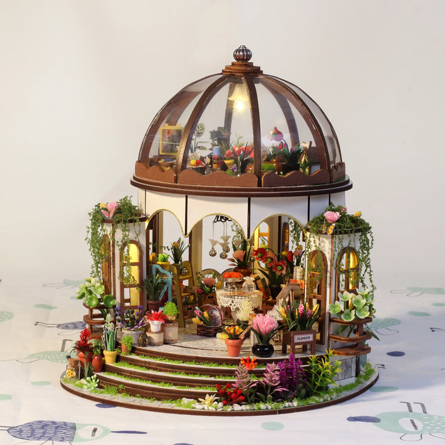 Step into a tranquil garden escape with this miniature kit-a sun-drenched sanctuary filled with flourishing plants, rustic charm, and peaceful vibes. This beautifully crafted greenhouse-style gazebo features delicate woodwork, glass-like panels, and an inviting open-air design surrounded by vibrant flowers, climbing vines, and cozy garden furniture. Whether you're dreaming of a relaxing afternoon under the sun or a quiet place to sip tea and tend to your plants, this miniature brings that dream to life-one 
