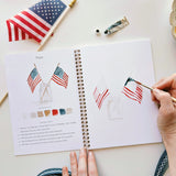 Twelve illustrations of flags, stars, and classic summer scenes — each pre-outlined with step-by-step instructions. Paintings take about thirty minutes from start to finish, making it approachable for first-time painters and a favorite for gifting.

A timely release for America's 250th anniversary in 2026. A strong May–July seller and a natural fit for home, gift, and patriotic-themed boutiques.

12 beginner-friendly illustrations
Thick 120lb watercolor paper&nbsp;
Lay-flat pages with spiral binding for has