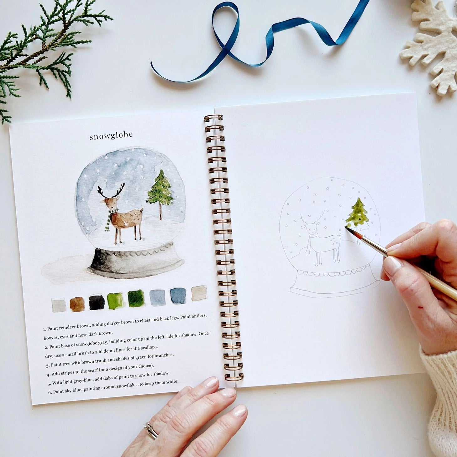 Twelve winter illustrations — a snowman, A-frame cabin, fair isle sweater, snow globe, ice skaters, mittens, and more — each pre-outlined with step-by-step instructions. Paintings take about thirty minutes from start to finish, making it approachable for first-time painters and a favorite for gifting.