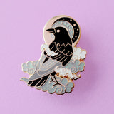 This enamel pin features a black crow surrounded by grey glittery clouds, and a starry moon with grey backgrounds. The pin is presented on a Glitter Punk backing card and is secured with 2 pin backs.

This pin is part of the Corvid Collection, an 8-part series of bird pins.&nbsp;

Measurements: 39mm