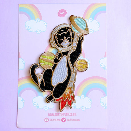This awesome Astronaut Cat patch features a tuxedo cat with a helmet and rocket ship playing with some planets.

Beautifully woven with multi coloured threads, this fabulous patch with brighten up any coat, bag or hat!

Measurements: 64mm x 110mm