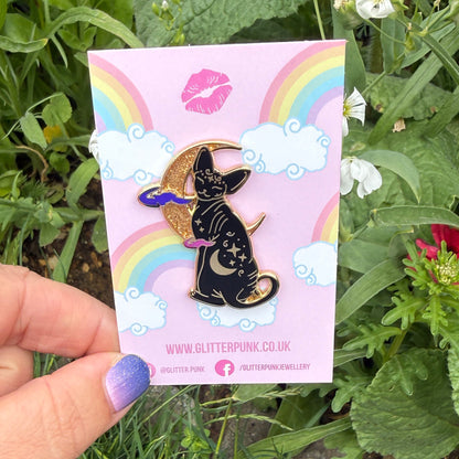 Cute, cuddly and clever – there’s no cat quite like a Sphynx! This fab enamel pin features a black Sphynx covered in mystical symbols, sitting in front of a crescent moon with 2 purple clouds.

The pin is 42mm (1.65”) tall, and is made from gunmetal hard enamel, with glitter and UV printed details. It's secured with 2 pink clutches to keep the pin in place.