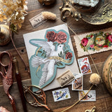 Folding card featuring a dove and roses, illustrated by Jessica Roux. Both doves and roses are symbols of romantic love, and this card is perfect for Valentine's Day, an anniversary, or to tell someone you love them. This card is inspired by Victorian Valentine cards.

Single card with envelope.
A2 size card in a cut-out shape of a dove with roses
Folded
Blank on the inside
Comes with a kraft paper envelope. Packaged in a cello sleeve.
Luxurious, soft-touch coating