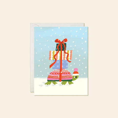Karen Schipper Greeting Card - Winter Turtle

A tiny turtle carrying a towering stack of presents makes this winter scene feel sweet, cheerful, and full of charm. This hand-illustrated Winter Turtle holiday card features a bundled-up turtle in a festive hat, wrapped gifts tied with a bright red ribbon, and soft falling snow for a whimsical seasonal design that feels easy to love.

A2 folded card, 4.25" W × 5.5" L
Printed in full color on FSC® certified white cover paper
Blank interior
Single greeting card +