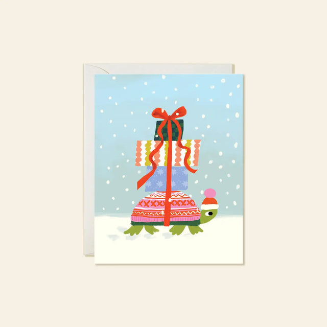 Karen Schipper Greeting Card - Winter Turtle

A tiny turtle carrying a towering stack of presents makes this winter scene feel sweet, cheerful, and full of charm. This hand-illustrated Winter Turtle holiday card features a bundled-up turtle in a festive hat, wrapped gifts tied with a bright red ribbon, and soft falling snow for a whimsical seasonal design that feels easy to love.

A2 folded card, 4.25" W × 5.5" L
Printed in full color on FSC® certified white cover paper
Blank interior
Single greeting card +