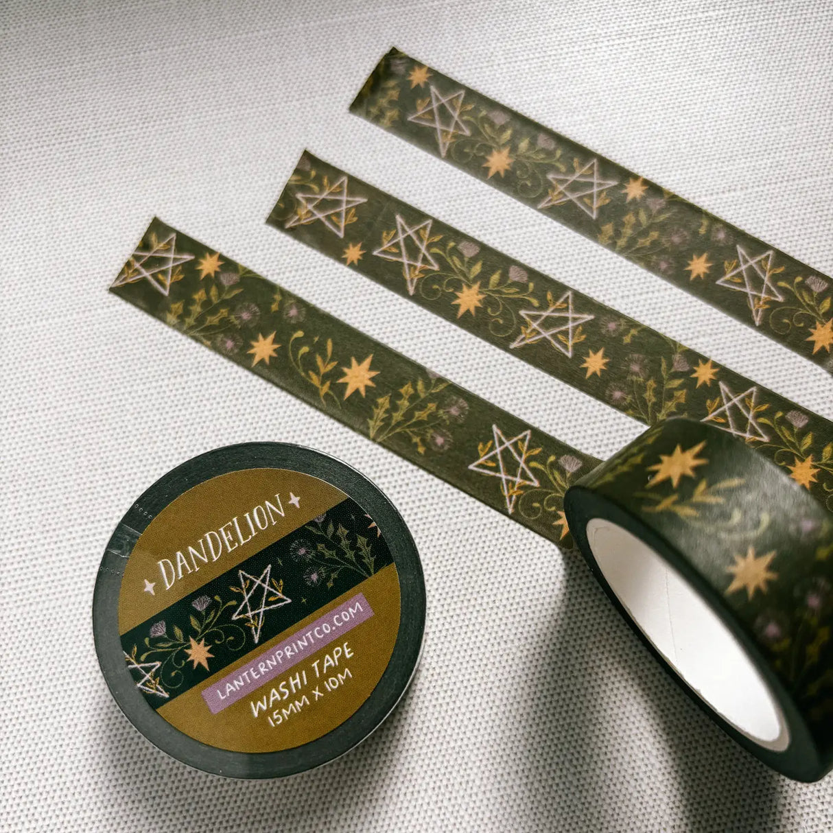 Removable Washi craft tape for journaling and gift wrapping; featuring dandelions and pentagrams on a dark green background.