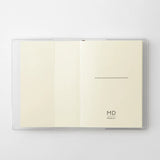 A transparent cover that fits snugly around your MD Notebook

This is a special cover that gently wraps your MD Notebook. The transparent cover protects the notebook from dirt without ruining its appearance.
It subtly protects your notebook from water and dirt without interfering with its characteristics. If you put the cover on with the glassine paper still wrapped around it, the inorganic feel of the vinyl will be softened.
Because it is transparent, you can enjoy the cover design, illustrations, and writ