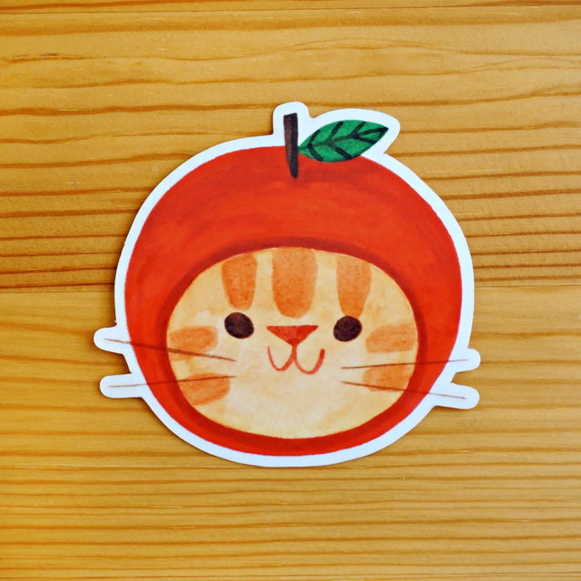 Sticker of a cat inside an apple on a wooden surface