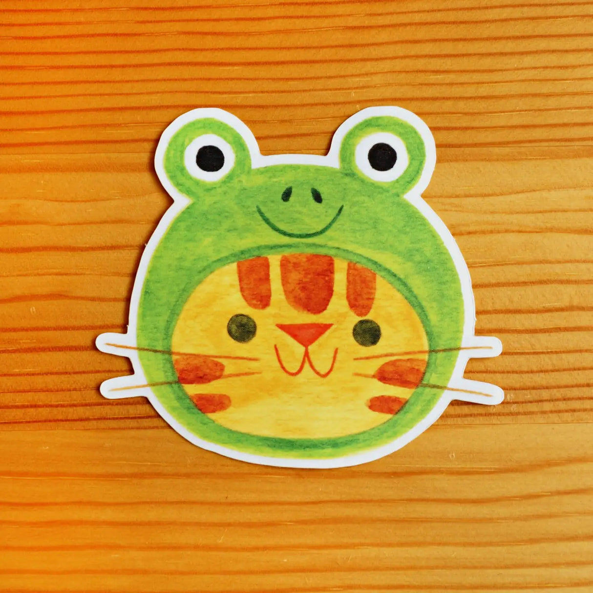 Cartoon frog sticker on a wooden surface