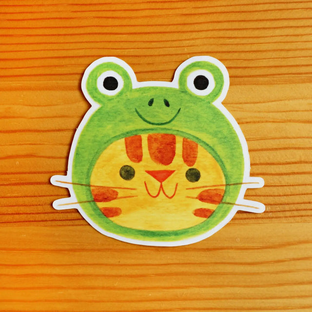 Cartoon frog sticker on a wooden surface