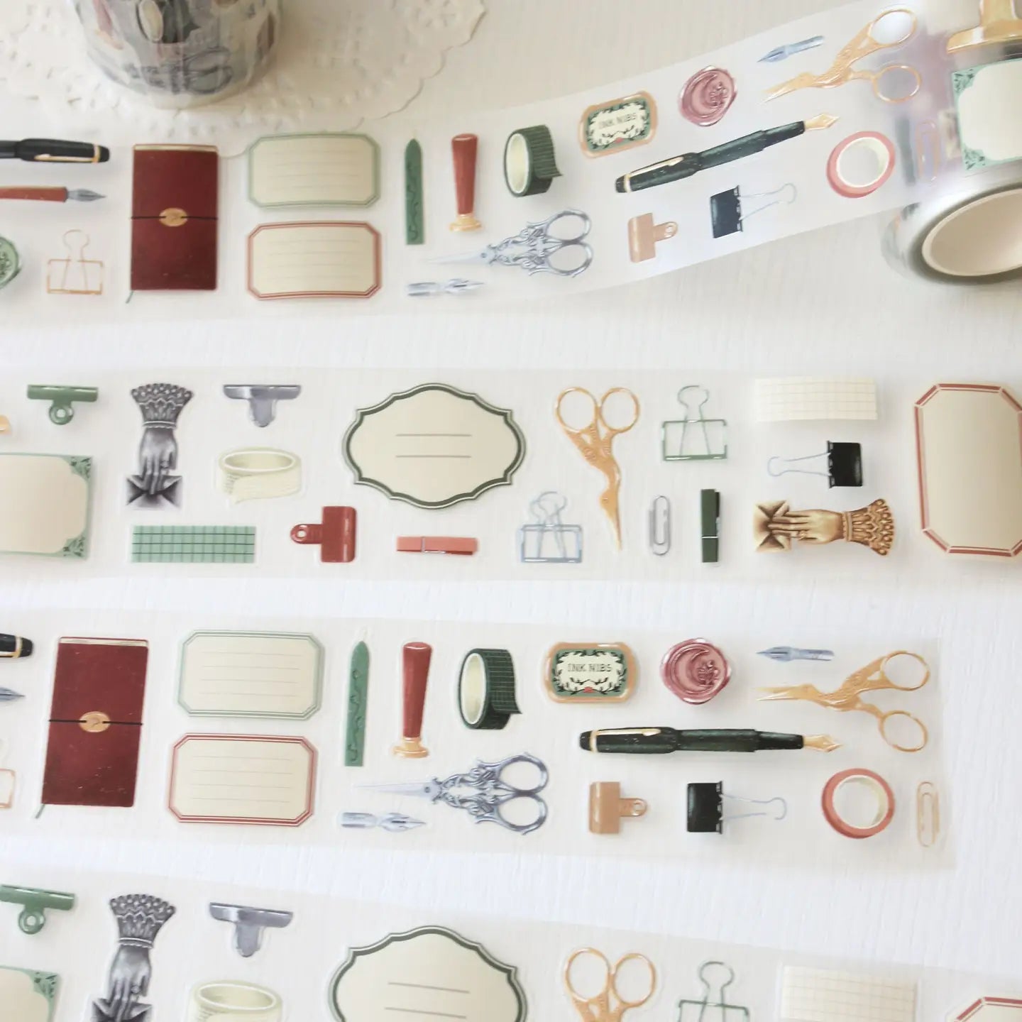 An updated version of our Stationery Essentials PET tape, now with a longer 50cm designer loop for even more creative possibilities.

This PET tape features hand-painted illustrations of vintage stationery such as wax seal stamps, fountain pens and ornate scissors. Designed by Rebecca and pre-cut for effortless use, it's perfect for journaling, collaging and adding a vintage aesthetic to any creative project.

Extra wide at 50mm with a matt transparent finish that layers cleanly over any background. No scis